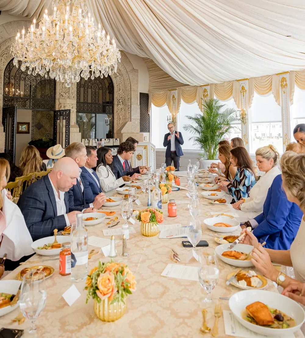 Guests dining at a long table during a Global Longevity Association gathering at Mar-a-Lago